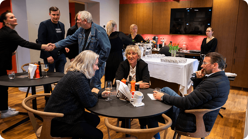 People networking at a professional event, shaking hands and conversing in a modern office space.